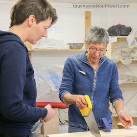 Woman sawing at a TouchWood South West carpentry class.