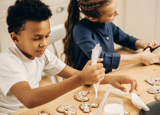 Children icing biscuits at baking class. 