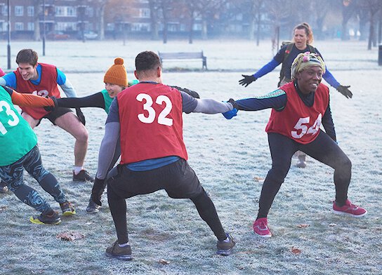 Participants at fitness class warming up outside in frosty park.