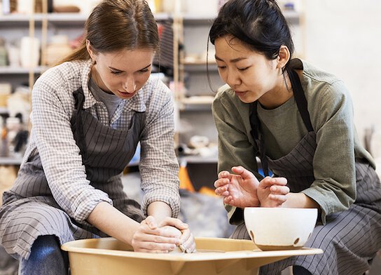 Women using potter's wheel at pottery class.