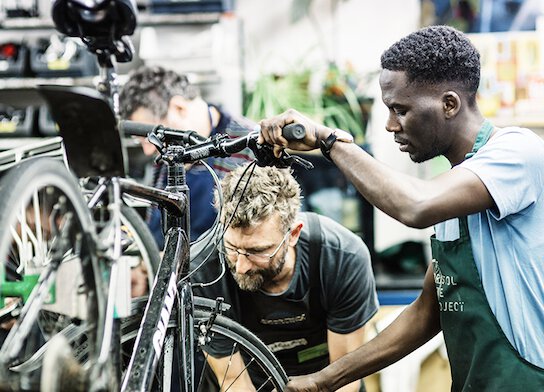 Bike mechanic and student working on bicycle at bike maintenance class.