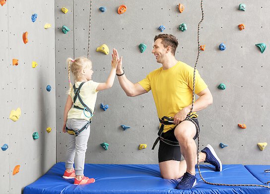 Klimleraar met meisje in het klimcentrum.