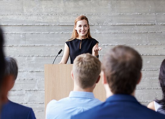 Woman giving speech at seminar event.