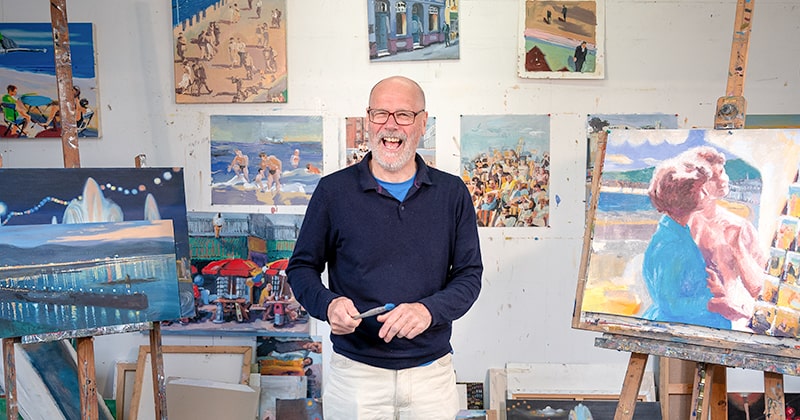 Teacher smiling and standing in front of paintings